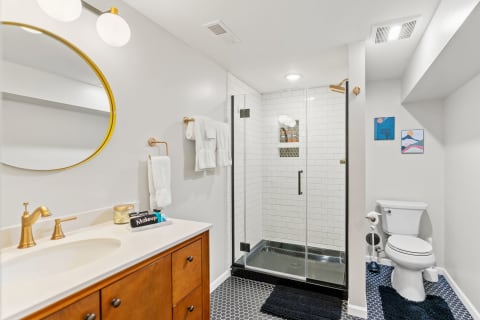 Modern bathroom with a large mirror, cabinet, and glass shower.