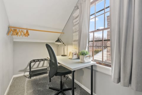 Cozy attic workspace with a desk and large window.