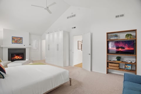 Bright and airy bedroom with vaulted ceilings, fireplace, and entertainment center.