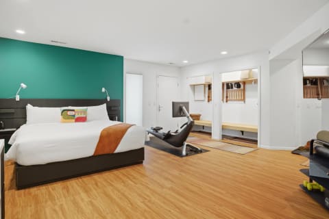 A contemporary bedroom featuring a teal accent wall, spacious bed, and a workspace area.