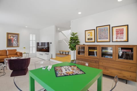 A modern living room with a green game table, leather sofa, and decorative art.