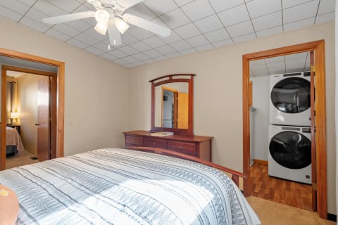 Interior view of a cozy bedroom with dresser, ceiling fan, and laundry area.