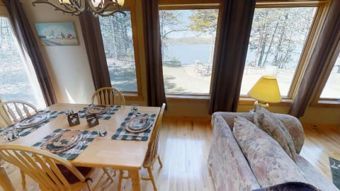 Dining area with a table set and a view of the lake through large windows.