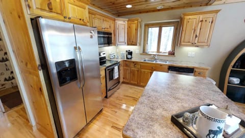 A rustic kitchen with wooden cabinets, stainless steel appliances, and a decorative tray with a mug on the countertop.
