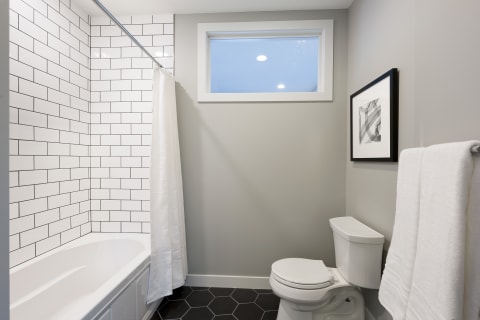 Minimalist bathroom with white subway tiles, black floor tiles, and a modern design.
