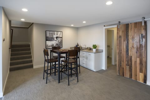 Modern basement dining area with a kitchen and sliding barn door.