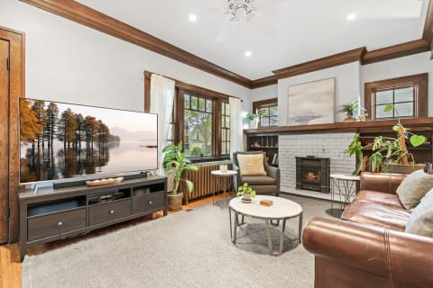 Living room featuring a TV, leather sofa, coffee table, and a fireplace.