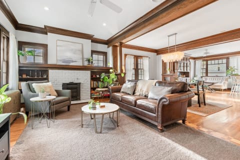 A warm living room featuring a brown leather sofa, wooden accents, and natural lighting.