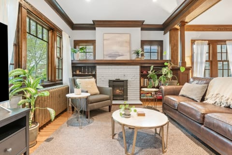 A cozy living room with a leather sofa, gray chair, and fireplace.
