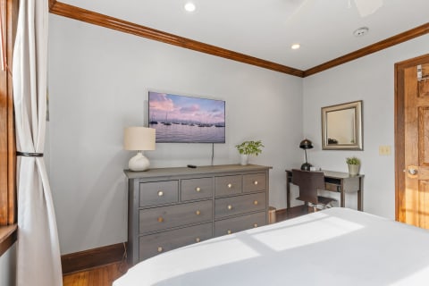 Cozy bedroom with gray dresser, television, and desk.