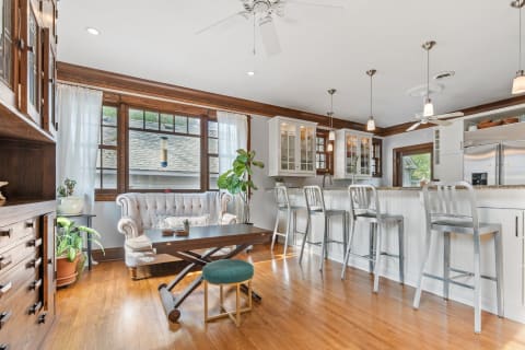 Stylish kitchen and living room with a tufted sofa, modern stools, and natural light.