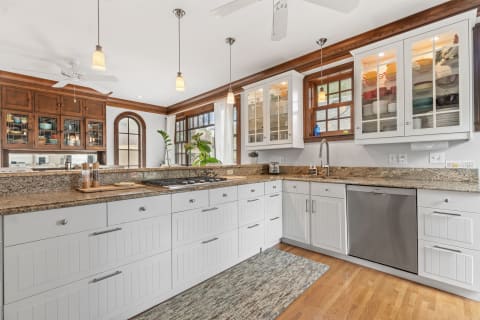 Modern kitchen featuring white and wood cabinets, granite countertops, and natural light from windows.