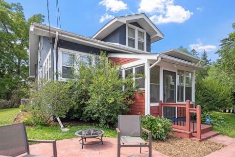 Exterior view of a two-story house with blue and red siding and a small patio.