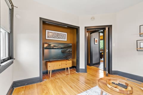 View of a stylish living room featuring a mounted television and wooden furnishings.