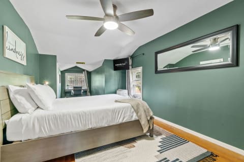 A stylish bedroom with a green wall, bed, and a desk.