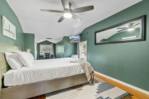 Stylish bedroom featuring green walls, a comfortable bed, and a workspace.