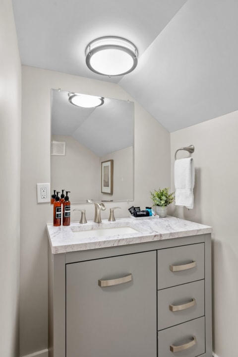 Contemporary bathroom featuring a marble countertop, modern faucet, and stylish decor.