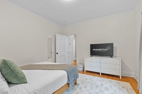 Cozy bedroom with a bed, dresser, and television.