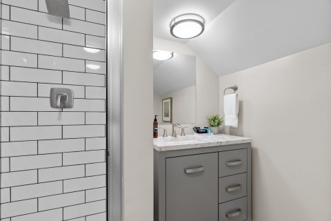 A stylish bathroom featuring a walk-in shower with subway tiles and a marble-topped vanity.
