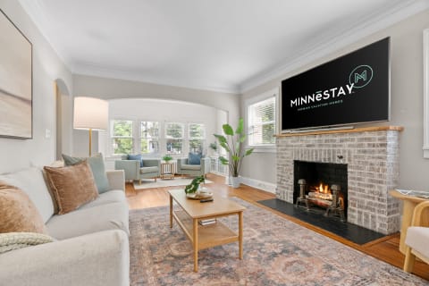 Living room with a fireplace, comfortable seating, and a TV displaying MINNESTAY logo.