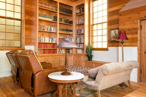 A comfortable library corner with leather chairs, a round table, and a collection of books.