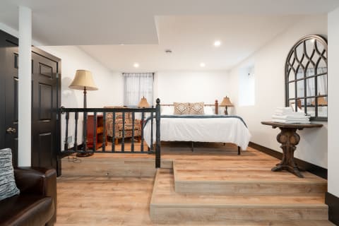 Cozy basement room with a bed, chairs, and wooden accents.