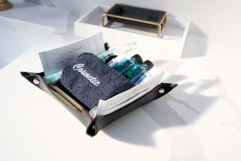 A black cosmetic pouch filled with toiletries on a marble countertop.