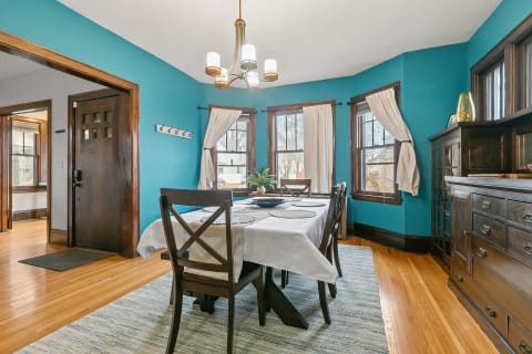 A dining room with turquoise walls, wooden furniture, and a bright chandelier.