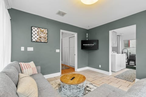 Cozy living room featuring gray walls, a cat painting, and a circular wooden coffee table.