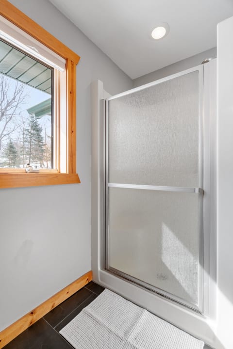 Sleek glass shower in a modern bathroom with a natural light from a nearby window.