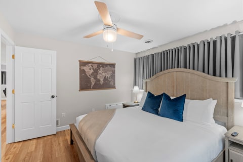 Cozy bedroom with a large bed, decorative world map, and gray curtains.