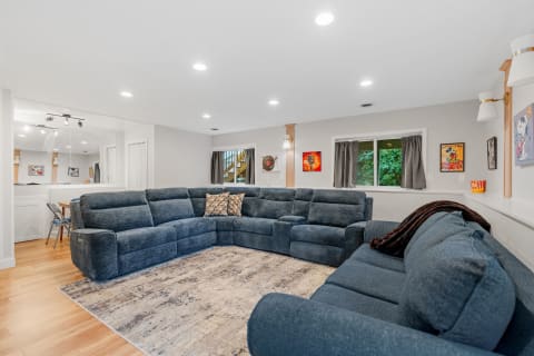 A modern living room with a navy blue sectional sofa, artworks on the wall, and large windows.