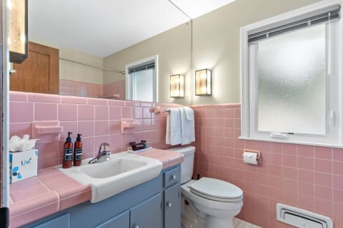 A bathroom featuring pink tile walls, a white sink, and modern fixtures.