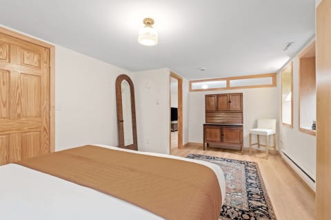 Warmly lit bedroom featuring a quilted brown bedspread, wooden accents, and a vintage cabinet.