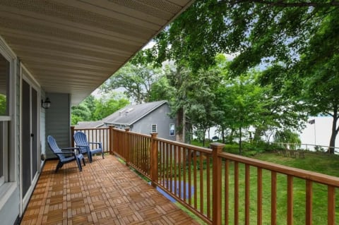 A balcony with blue chairs surrounded by greenery and a water view.