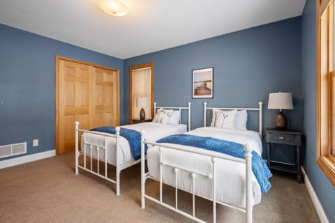 A cozy bedroom with two twin beds, blue walls, and wood accents.