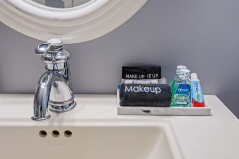 Bathroom sink with chrome faucet and organized countertop featuring makeup and dental care products.