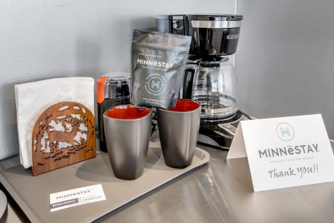 A coffee station featuring mugs, a coffee maker, and a thank-you card.