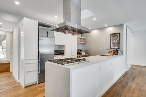 Modern kitchen with white cabinets, stainless steel appliances, and hardwood flooring.