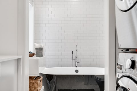A clean and modern bathroom featuring a freestanding bathtub and laundry appliances.