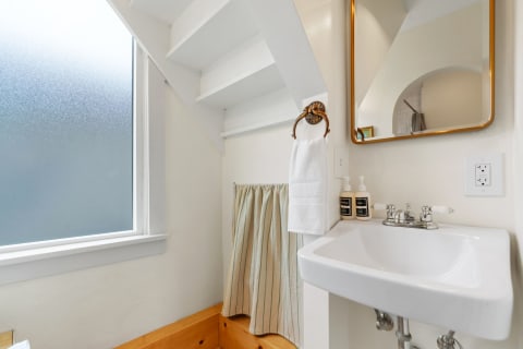 Modern bathroom featuring a frosted window, white sink, and decorative towel holder.