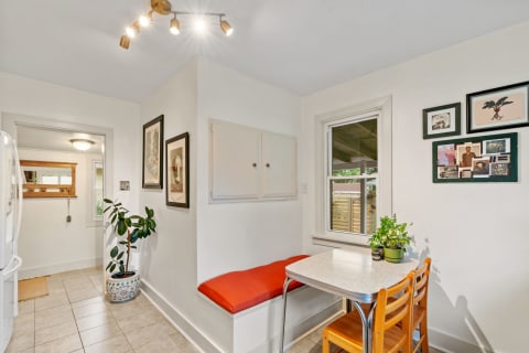 Kitchen nook featuring a table with two chairs and a built-in bench with an orange cushion.