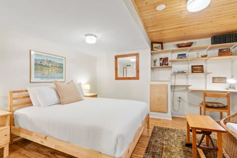 Minimalist bedroom with a wooden bed, warm lighting, and shelves displaying decor.