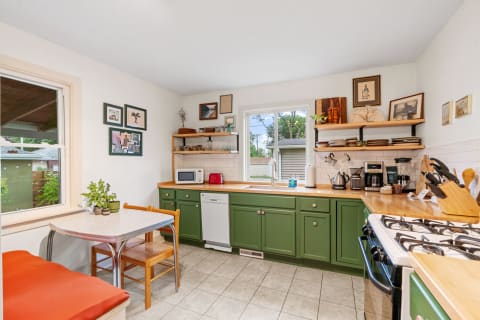 Charming kitchen with green cabinets, wooden counter, and cozy dining nook.