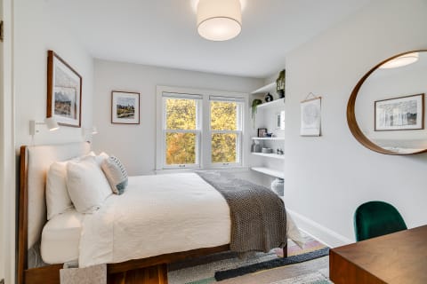 Cozy bedroom featuring a bed, decorative elements, and large windows with autumn views.