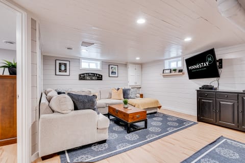 Cozy basement living space featuring a sectional sofa, wooden coffee table, and wall-mounted TV.