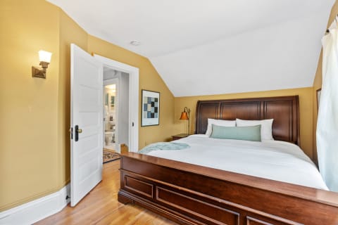 A warm and inviting bedroom with a wooden bed, soft linens, and an adjoining bathroom.