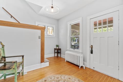 Cozy entryway featuring a staircase, wooden flooring, and vintage decor.