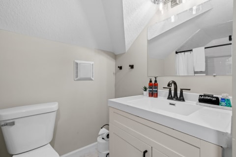 A small attic bathroom with a white toilet, modern sink, and stylish decor.