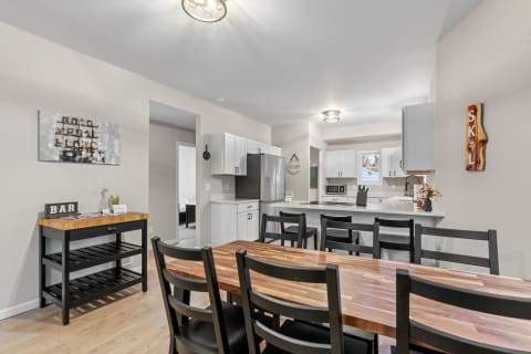 Modern kitchen and dining area featuring wood and black accents, with a dining table and stylish decor.